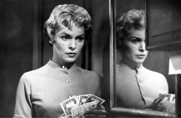 Black and white scene of Janet Leigh from Hitchcock's "Psycho" looking concerned with money in her hands.