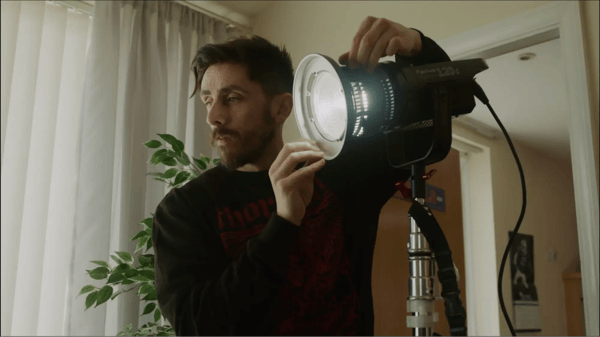 Man holding and positioning film light in a house.