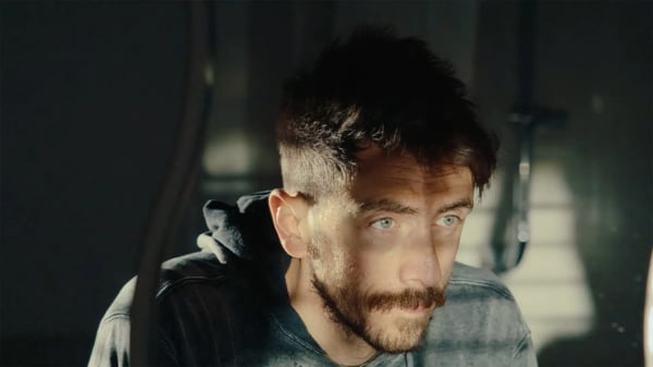 Cinematic shot of man looking into distance with light from window cutting across his eyes. 