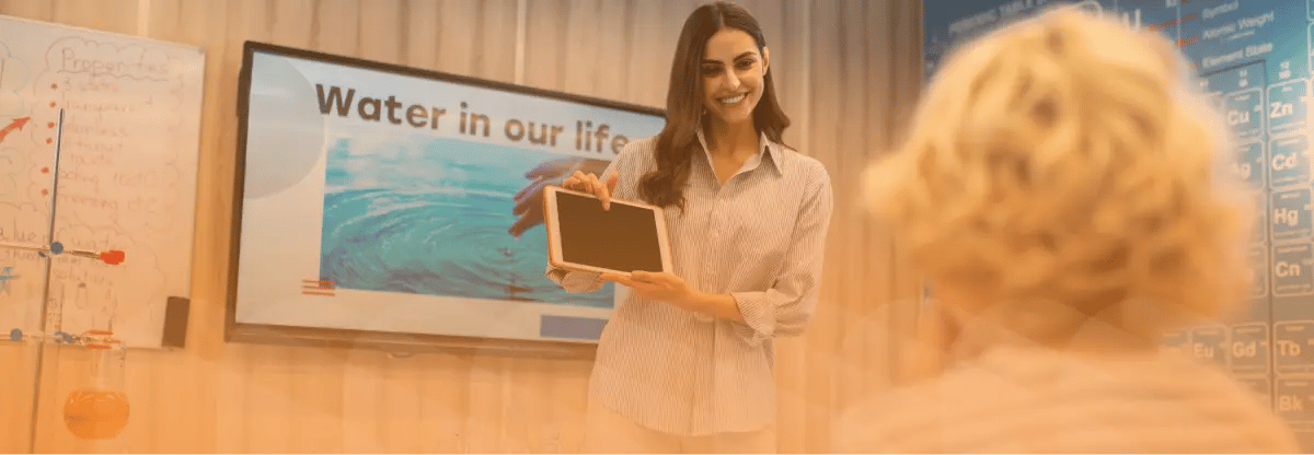 Educator pointing to tablet in a classroom.