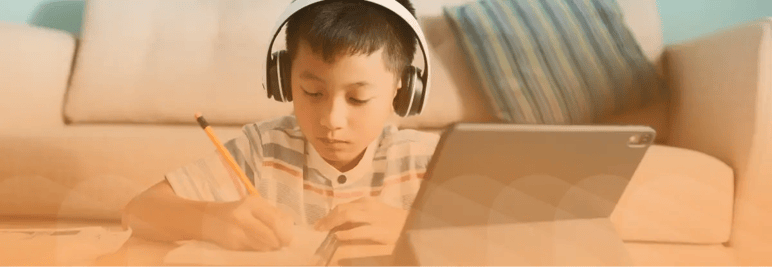 Young child with headphones, working on laptop. Light orange overlay.