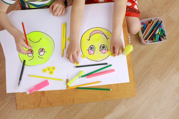 Students drawing happy and sad faces.