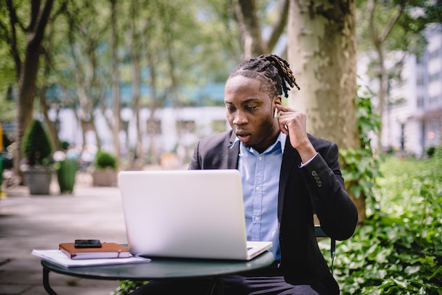 Businessman with airpods on a laptop in a street cafe