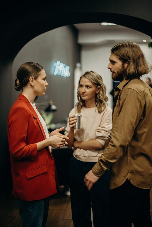 Trio of co-workers communicating in an office hallway.