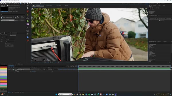 Producer in grey hat and brown coat outside shown through Adobe After Effects software.