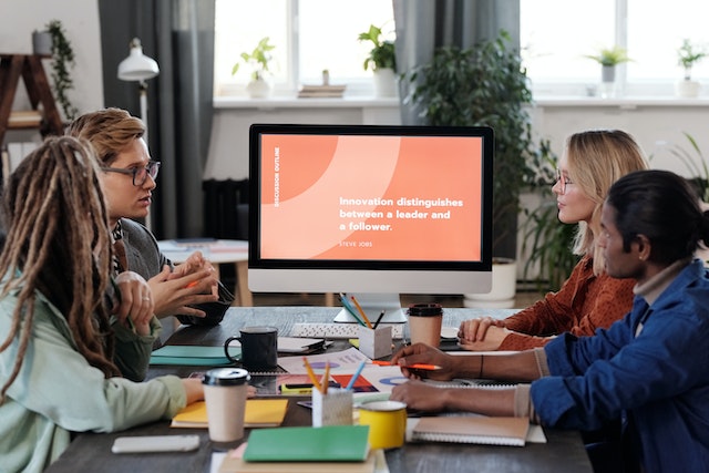 Four people gathered around a computer presentation engaged by the topic