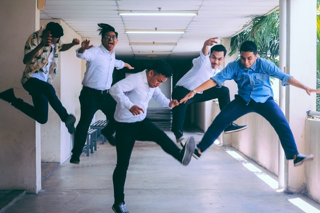 Group of men at work, all playfully jumping into the air