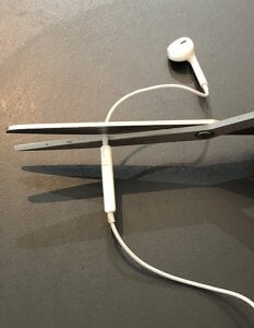 Apple wired headphone, with microphone and headphone being separated by scissors.