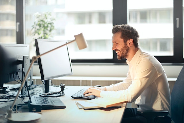 Man smiles sitting behind computer at work