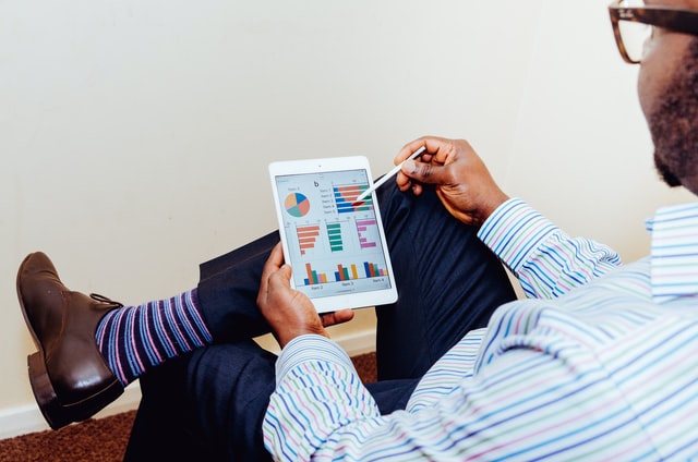 Business man sitting with point-pen and a tablet looking at graphs.