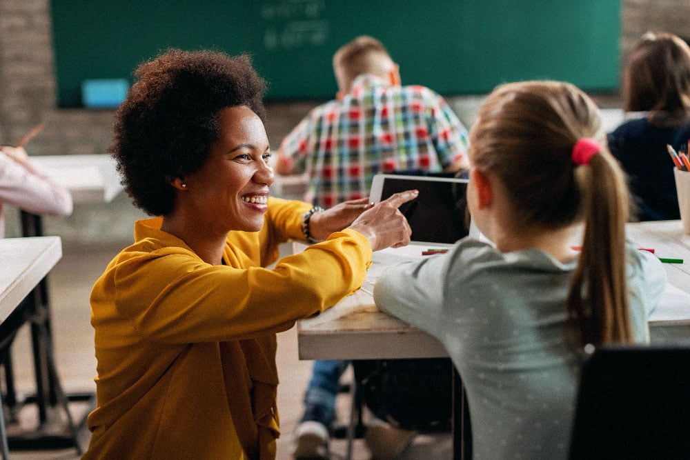 Teacher showing student how to use tablet for online learning