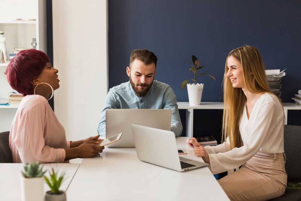 Three business colleagues sitting in front of laptop making corporate videos.jpg