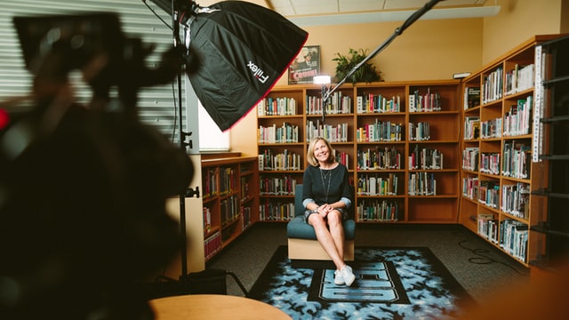 Woman sitting on chair with camera and lighting.