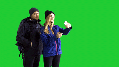 A man and a woman taking a selfie in front of a green screen