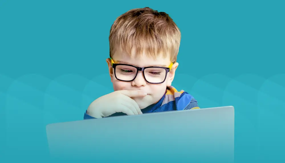 Young boy working on laptop. Teal background.