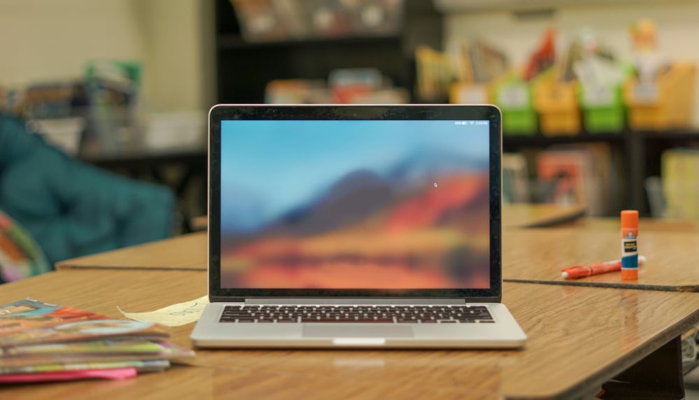 Laptop screen open in a classroom setting.