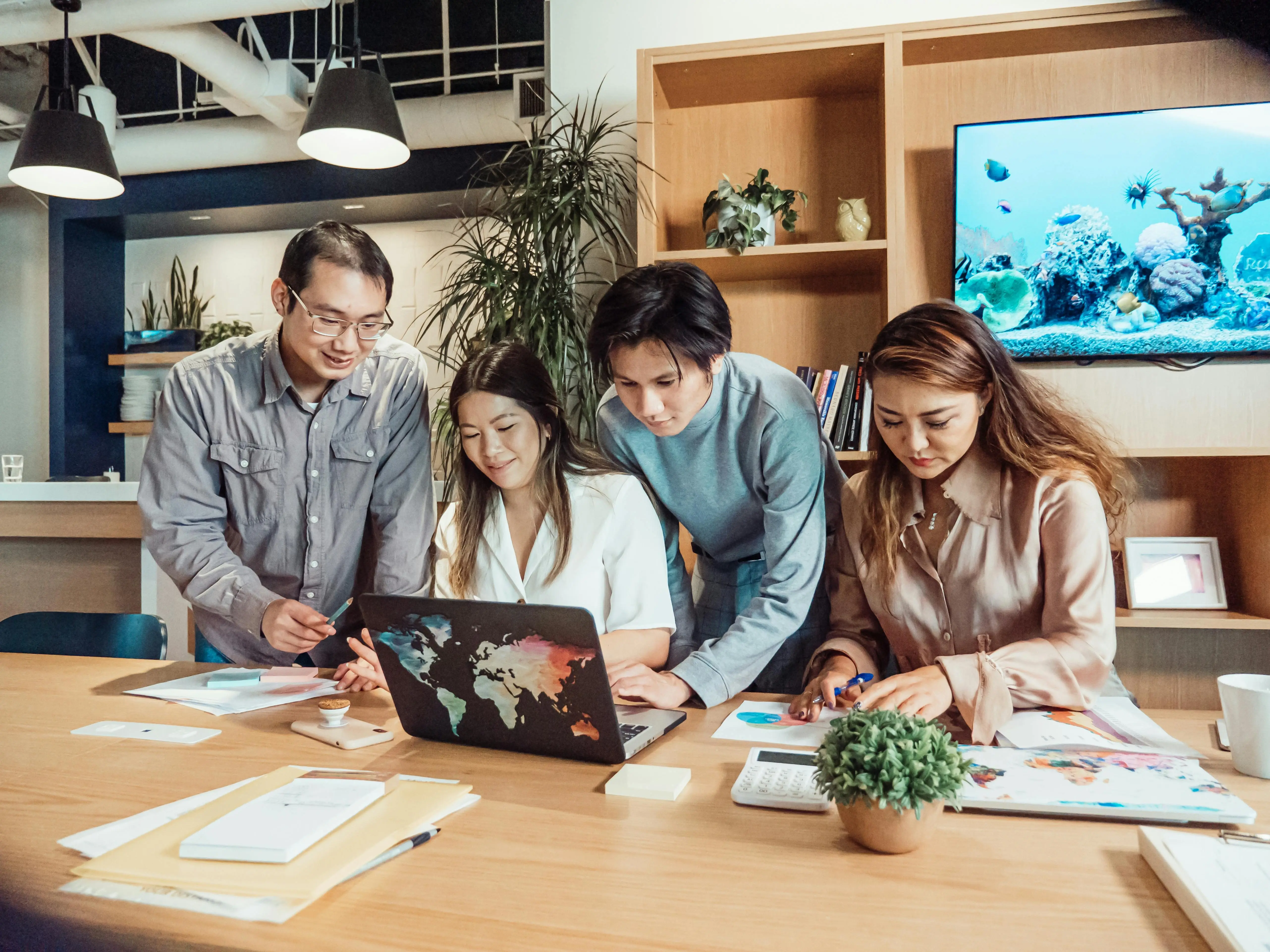 Corporate team working together on a desk and around one laptop computer.