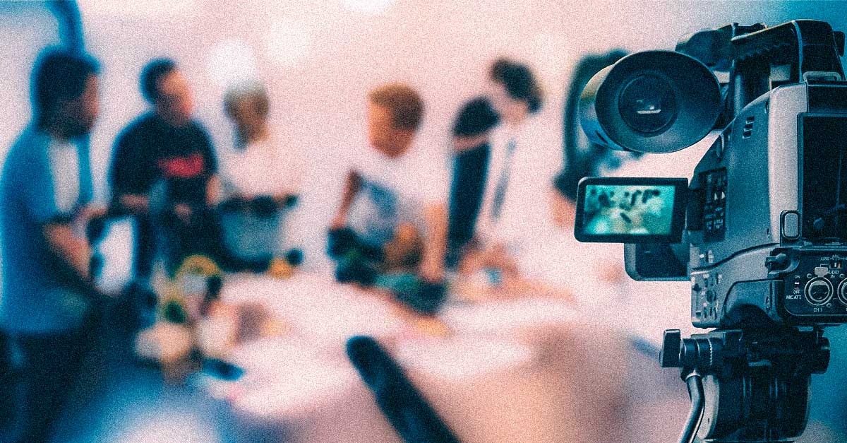 Closeup of camcorder filming a group of blurry people in the background