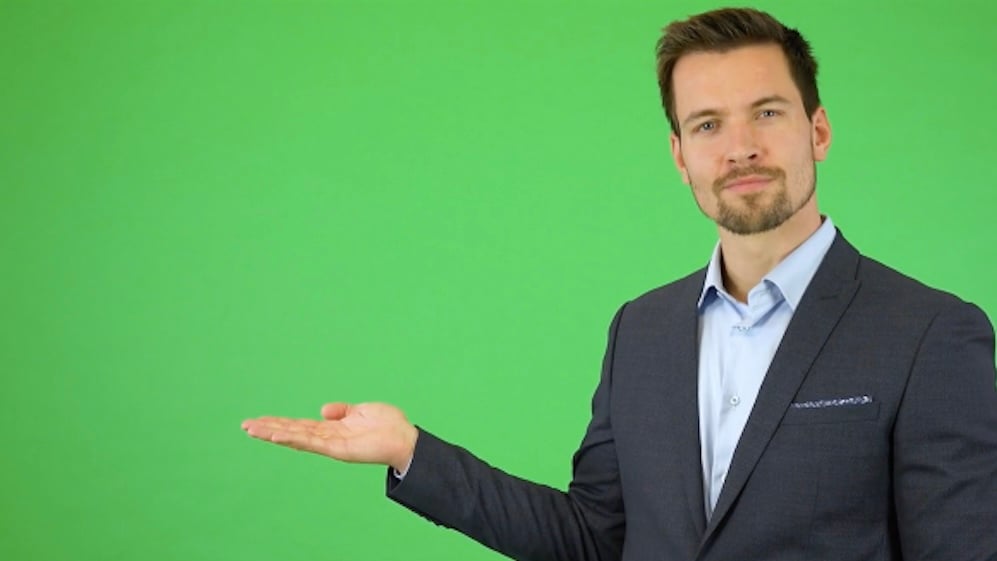 Professional businessman gesturing with his palm up in front of a green screen background