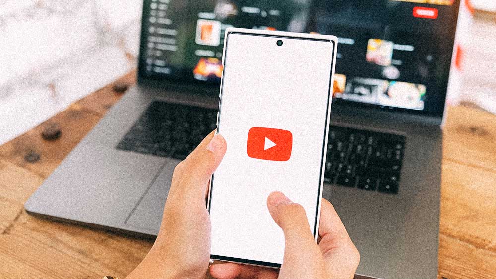 Person holding a phone with the YouTube logo visible