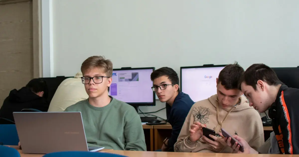 Four male students in a computer room working together on a project.
