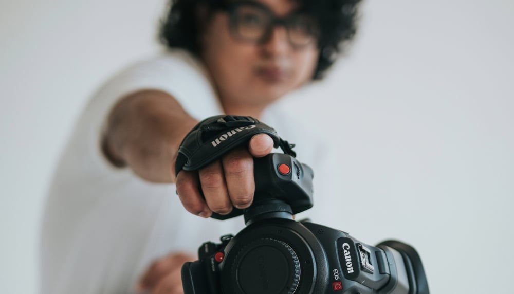 Student pointing with a film camera in their hand.