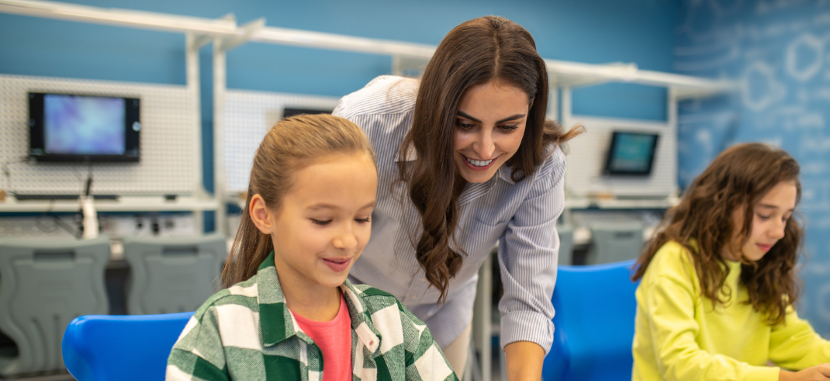 Female instructor supporting young learner while she works.