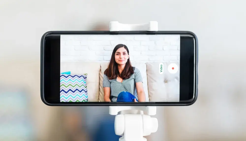 Woman sitting on a couch being recorded for a video