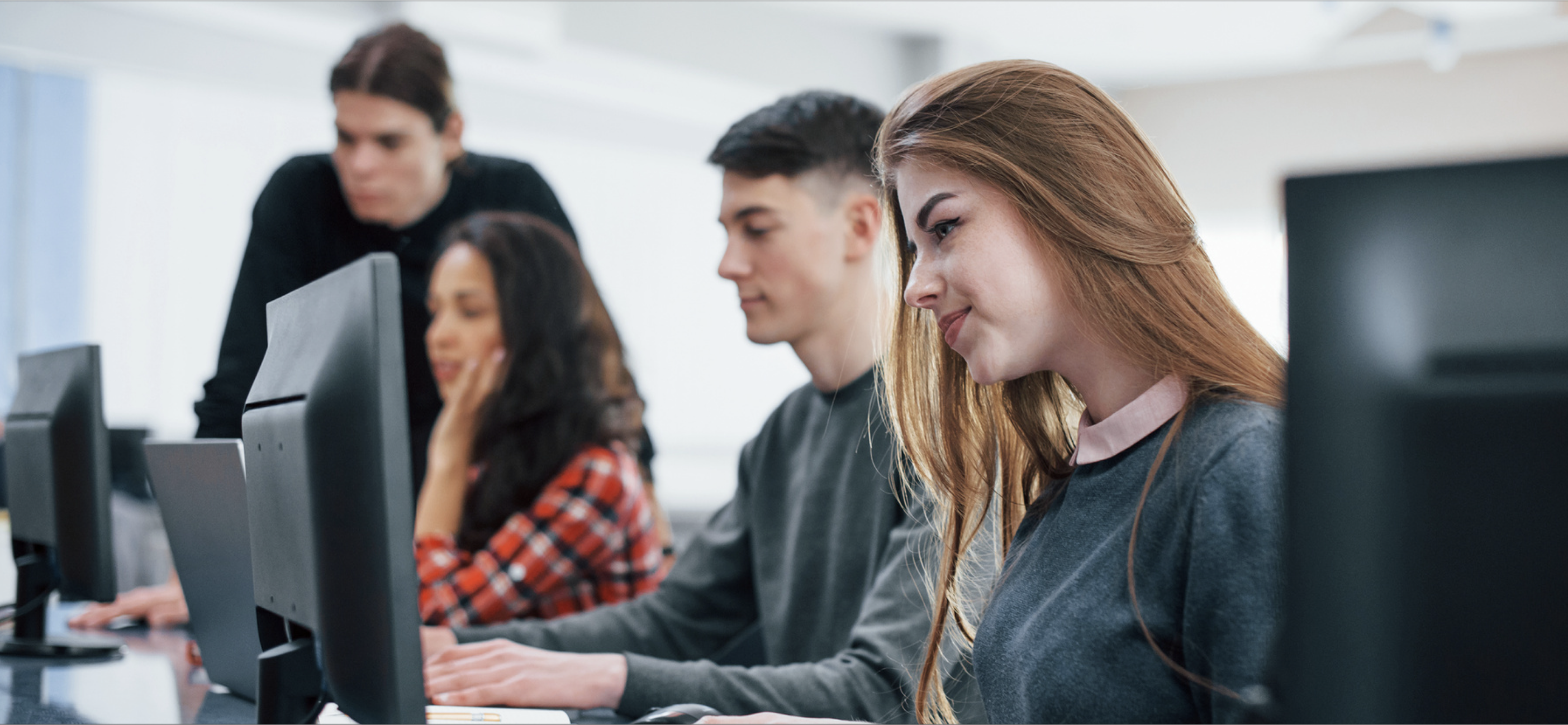 Group of higher ed students all sitting at computer in a row