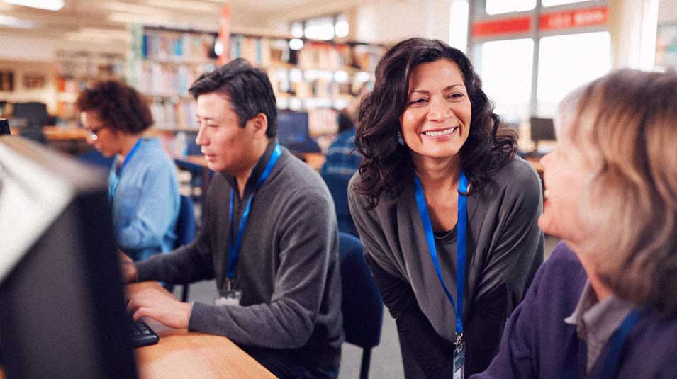 Educators in library sitting at computers for professional development.