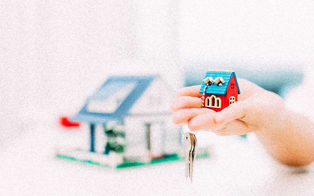 Closeup of a hand holding a keychain with a miniature house
