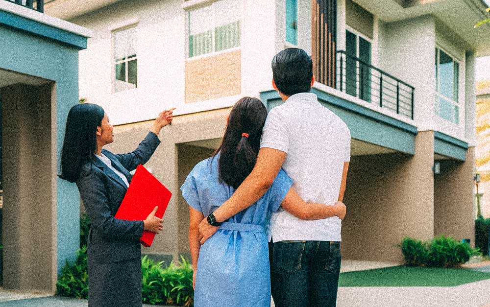Real estate agent showing a couple the outside of a home