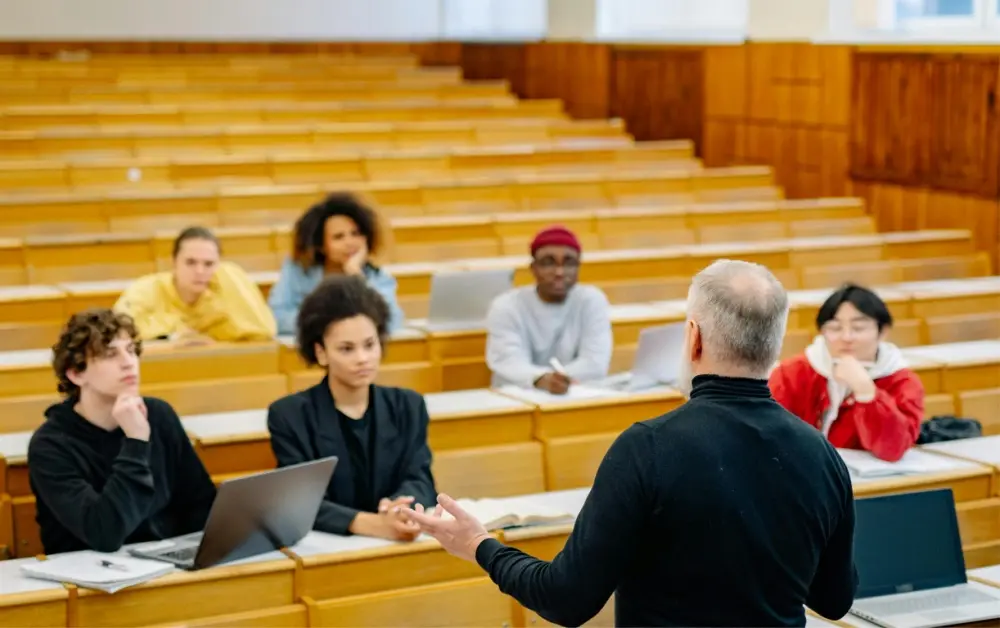 Higher education students sitting in a lecture hall as instructor teaches.