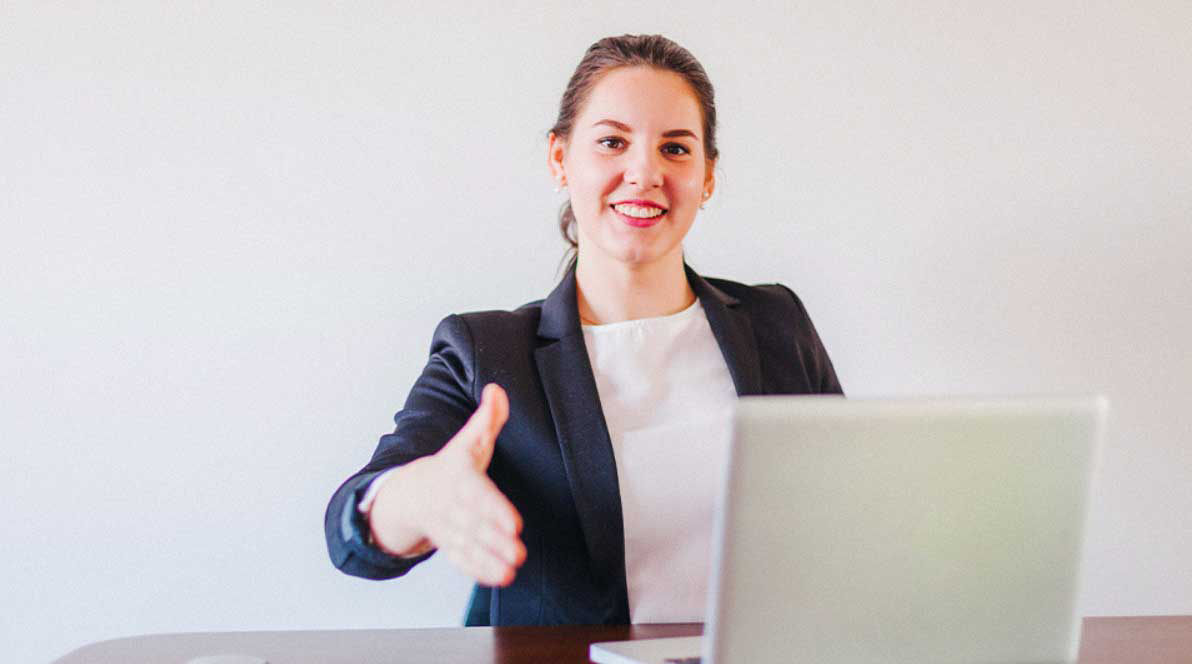 Business woman holding hand out in front of laptop