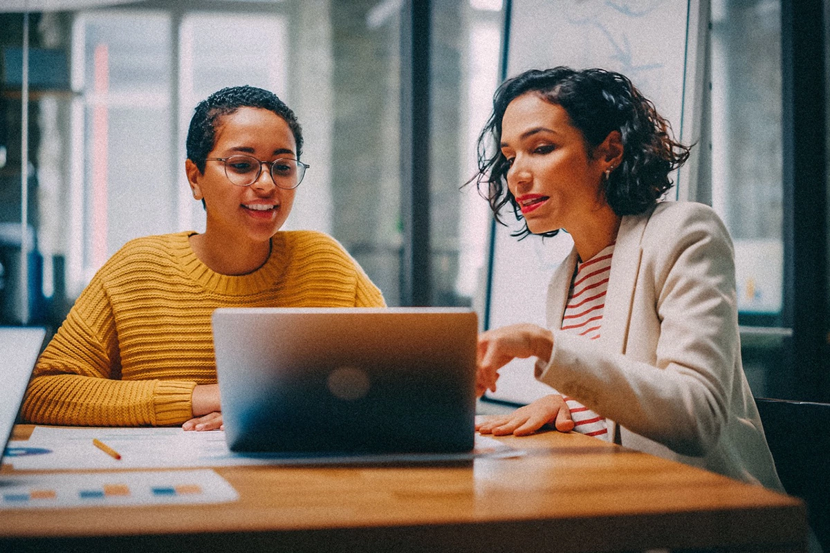 Two women sitting in front of laptop to make video online