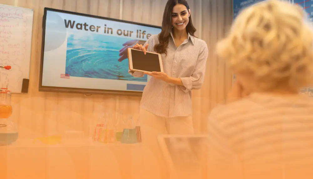 Professional holding a tablet towards class with presentation in background and yellow gradient overlay