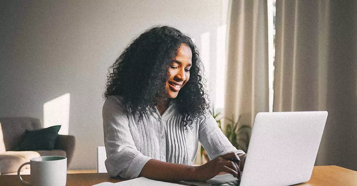 Woman smiling with laptop open as she works.