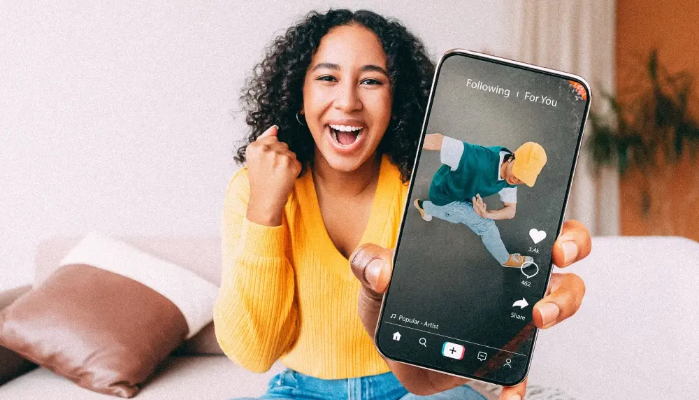 Woman smiling and showing the viewer her phone of a TikTok social media video