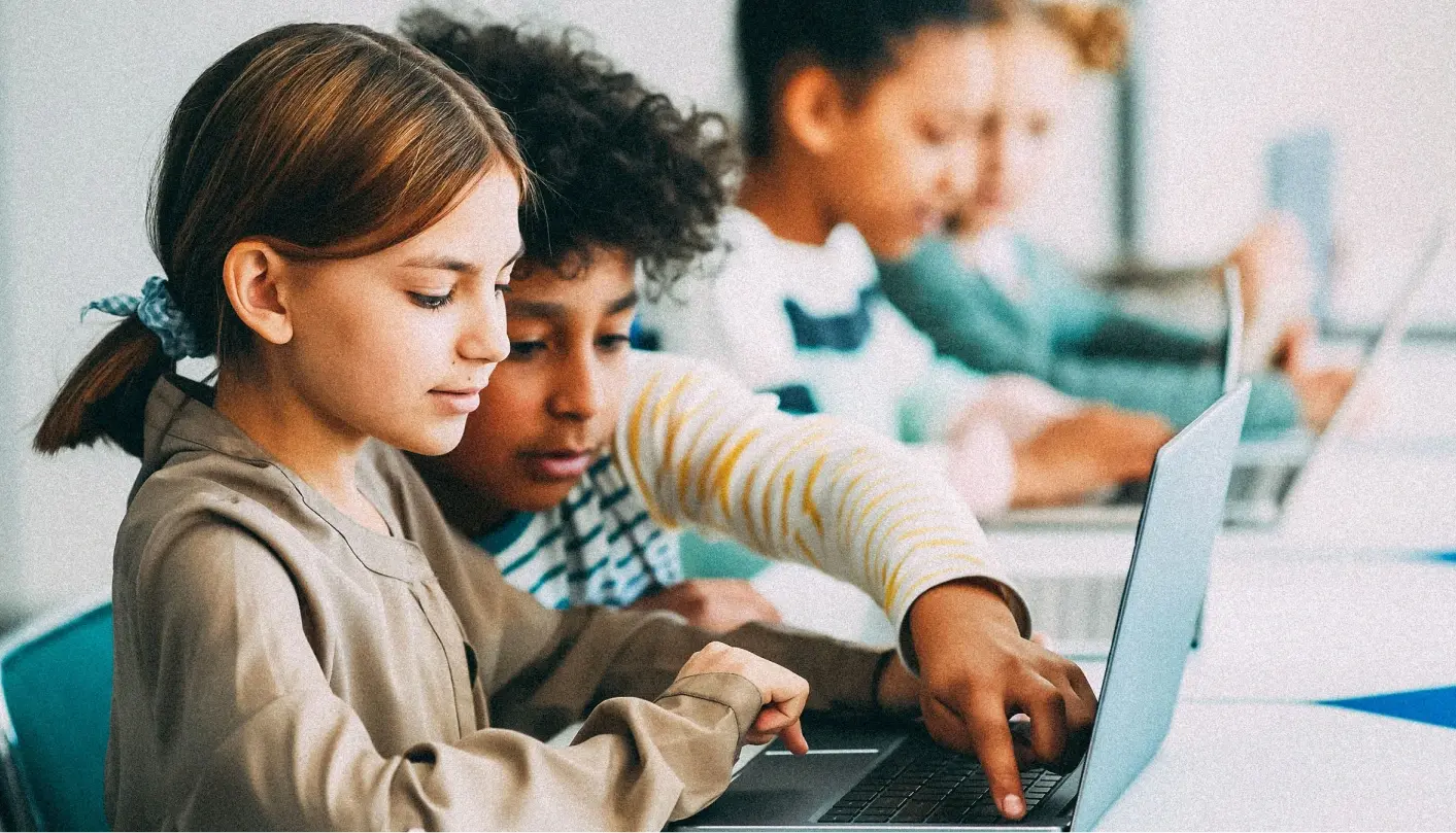 Boy and girl classmates collaborating behind a laptop