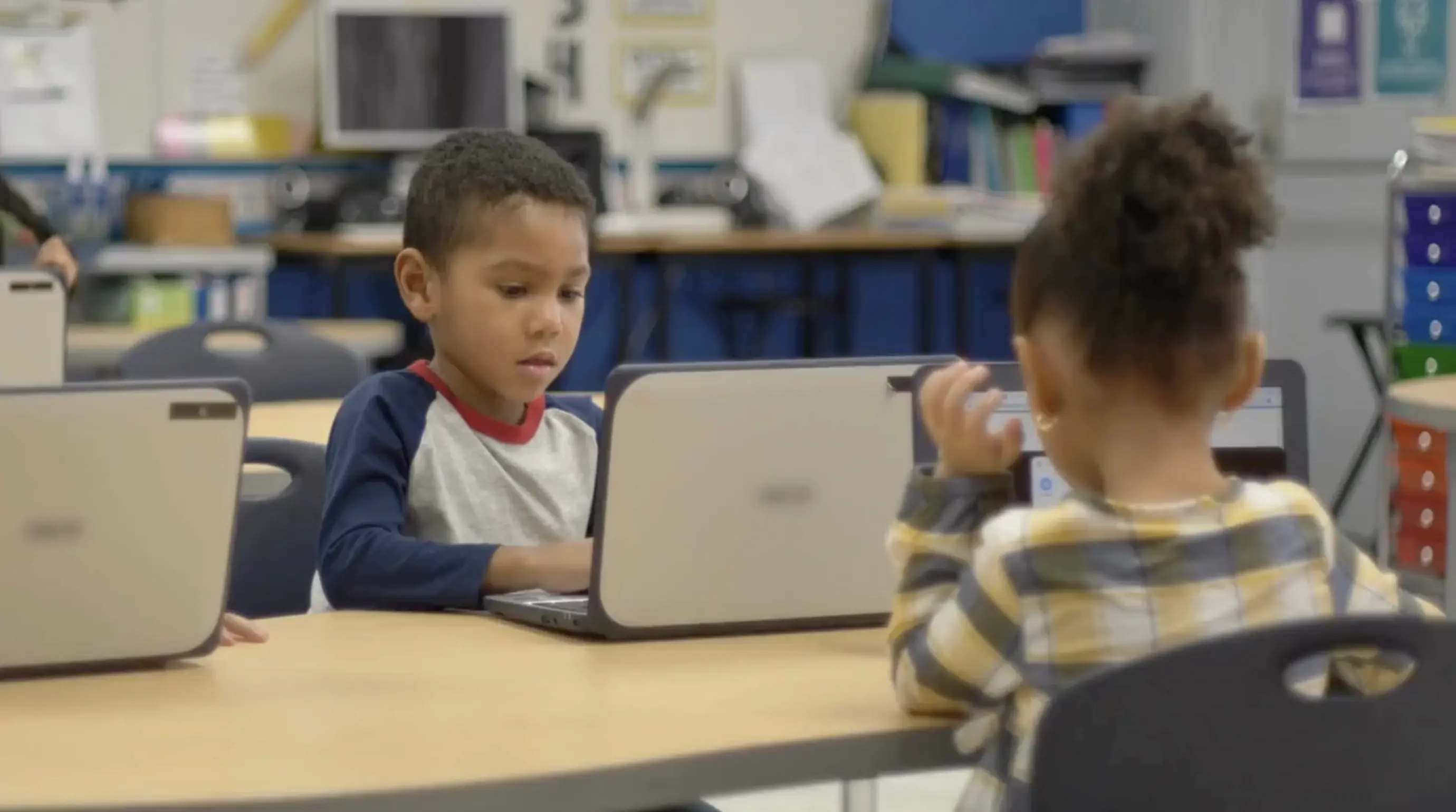 Young student engaging in his computer at a classroom desk