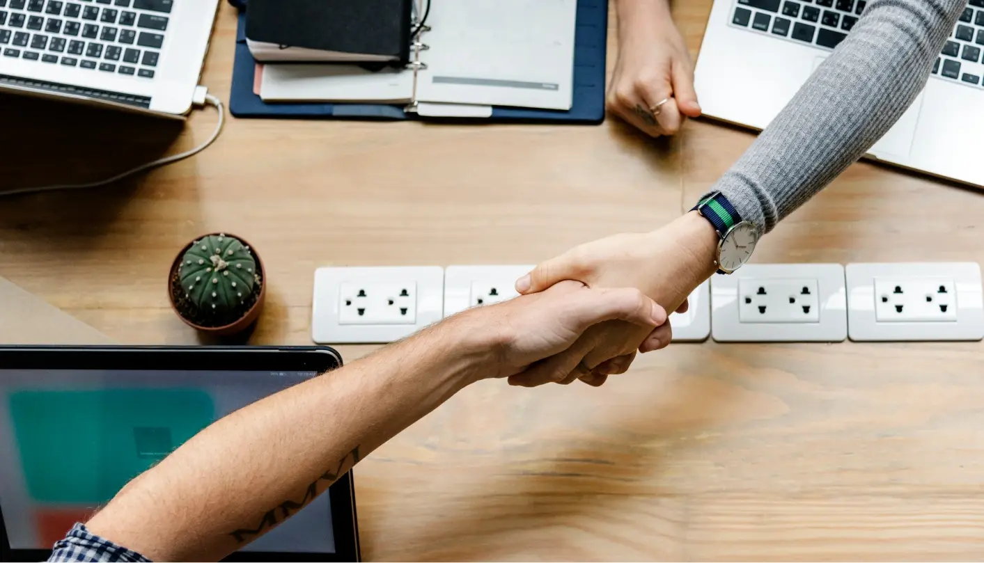 Two people shaking hands in business as they collaborate in an office environment