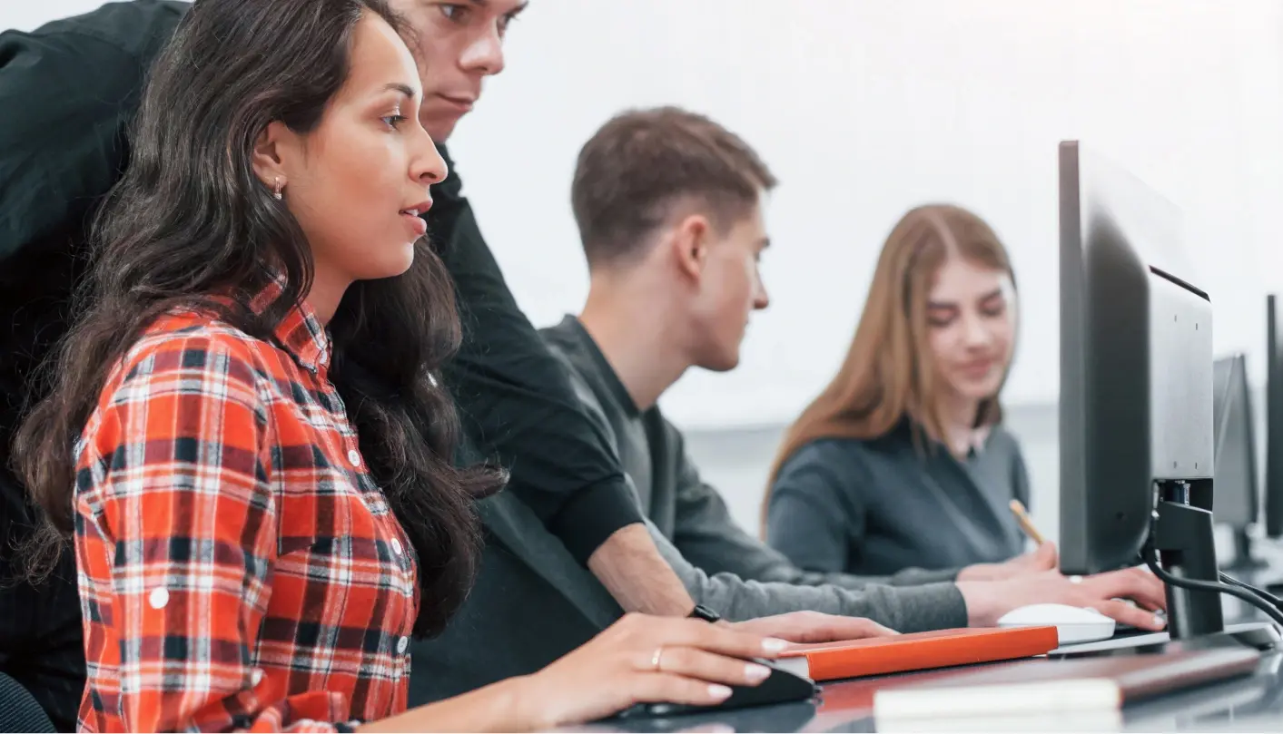 Woman using computer with other students around.