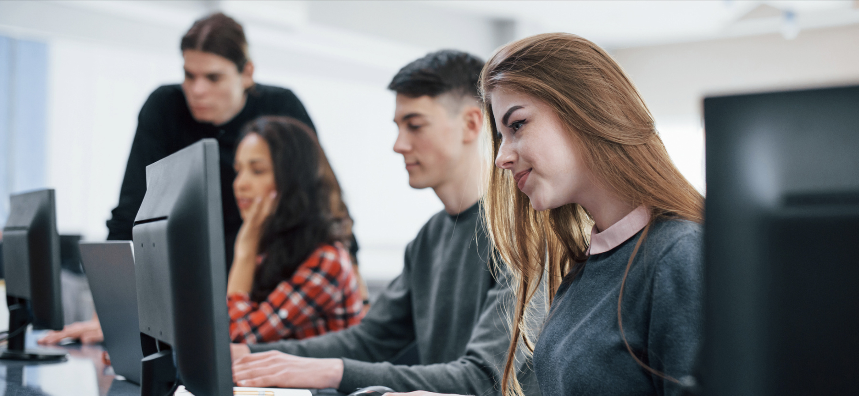 Learners sitting near each other while learning on computers.